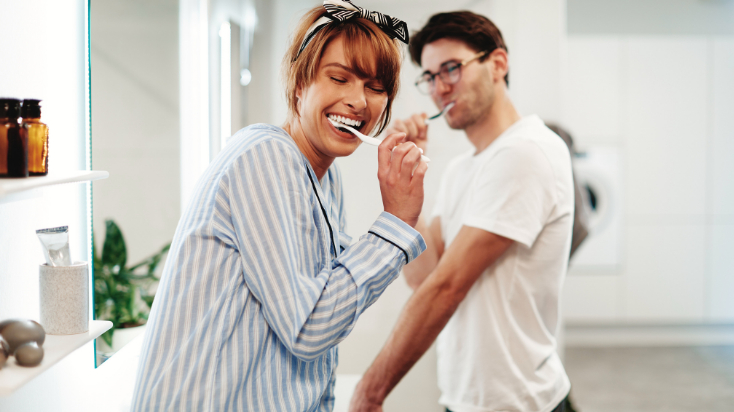 two people smiling and brusing teeth